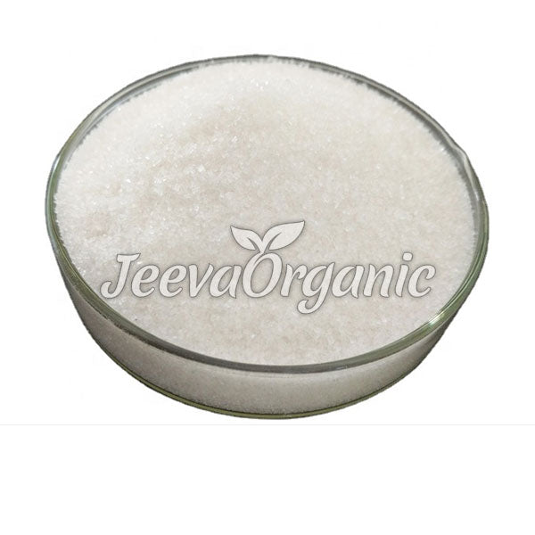 A glass bowl filled with fine white sugar, branded with 'Jeeva Organic' logo, set against a plain white background.