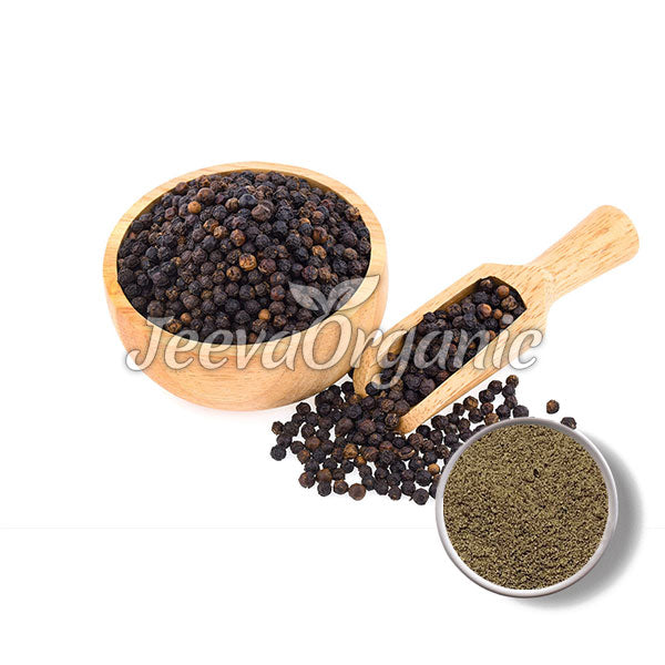 A wooden bowl filled with whole black peppercorns, a scoop with more pepper, and a small dish of ground black pepper.