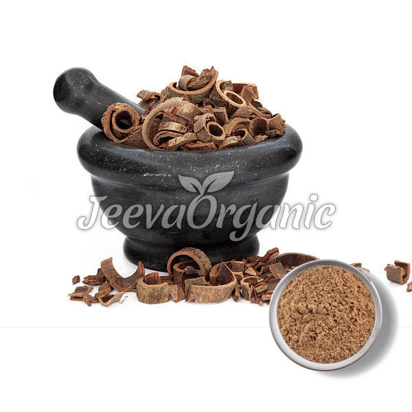 A black mortar and pestle filled with curled brown herb pieces, next to a small bowl of brown powder.