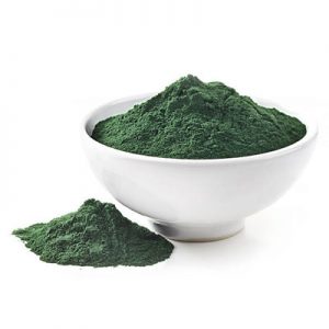 A bowl and mound of bright green spirulina powder, showcasing its vibrant color and fine texture against a white background.