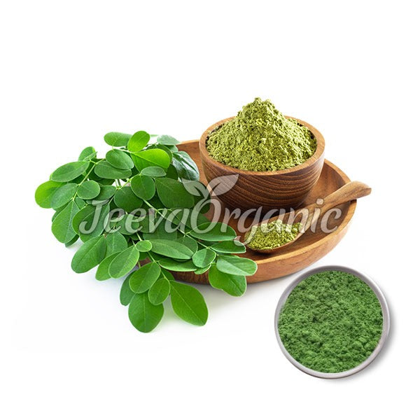 Green moringa leaves beside two bowls of moringa powder on a wooden plate, showcasing organic health products by Jeeva Organic.