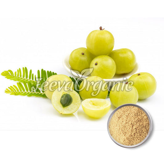 Fresh green amla fruits with sliced pieces revealing the seed, accompanied by a bowl of amla powder and green leaves.